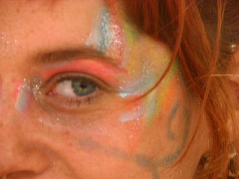 Face painted in rainbow colours