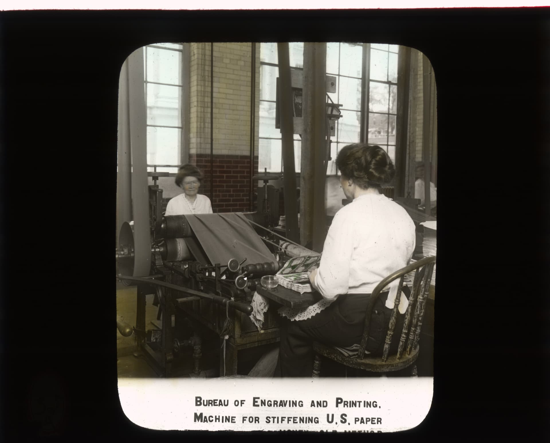 Photograph of Female Employees Operating Machines for Stiffening Paper - DPLA - 88763f6db7b3063d42bcb11a241d95