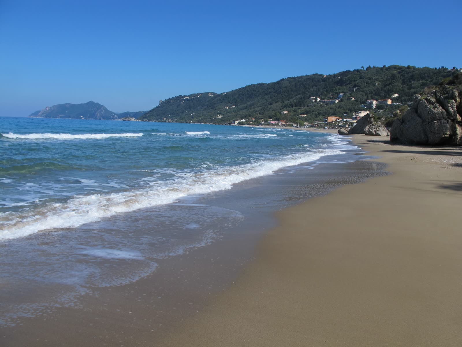 The sand and shallow water of Agios Gordios beach