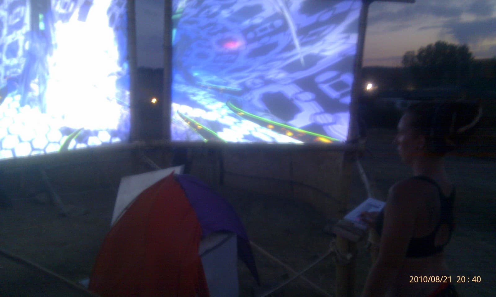 Talking beside the lit screens at dusk, Boom 2010