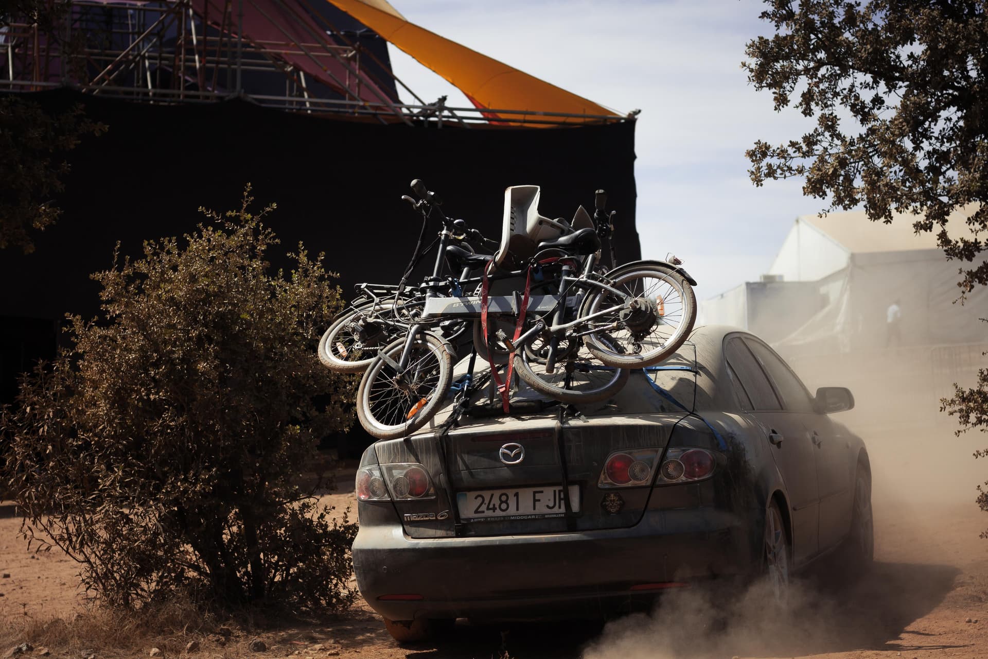 Car with bicycles arriving through the dust