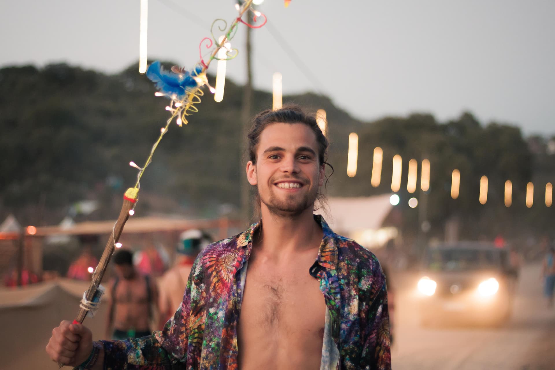 Visitor carrying a decorated staff at dusk